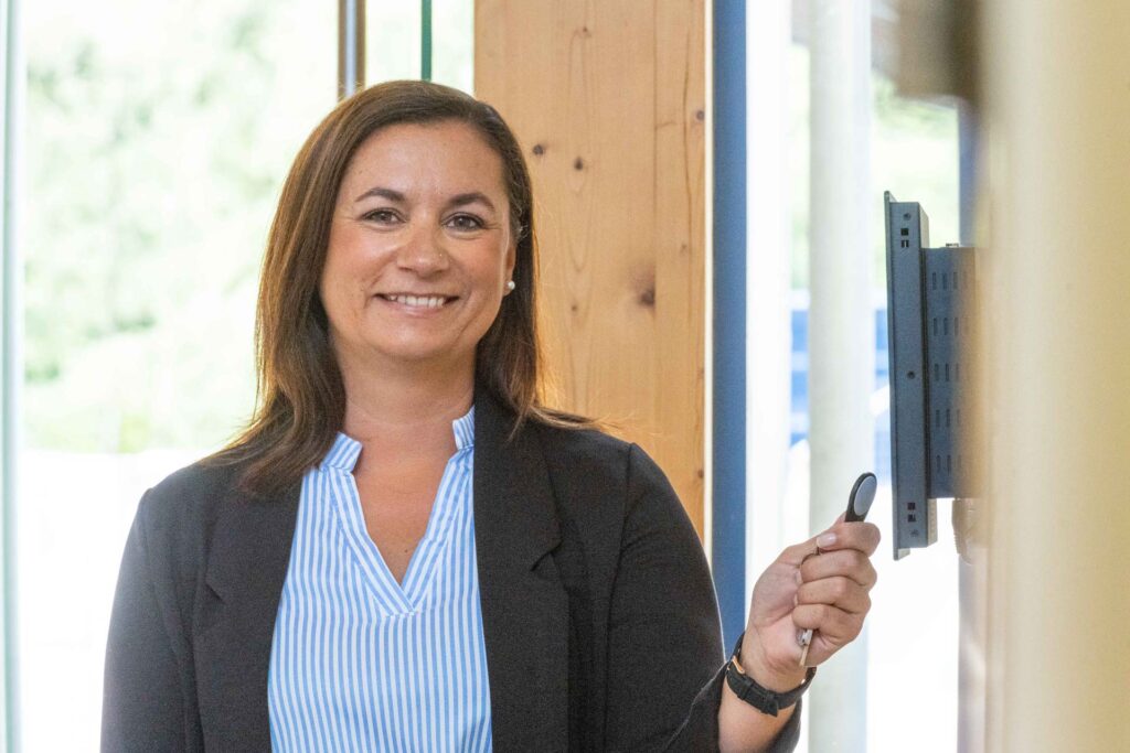 Frau stempelt an einem Zeiterfassungsterminal von asut Computer.